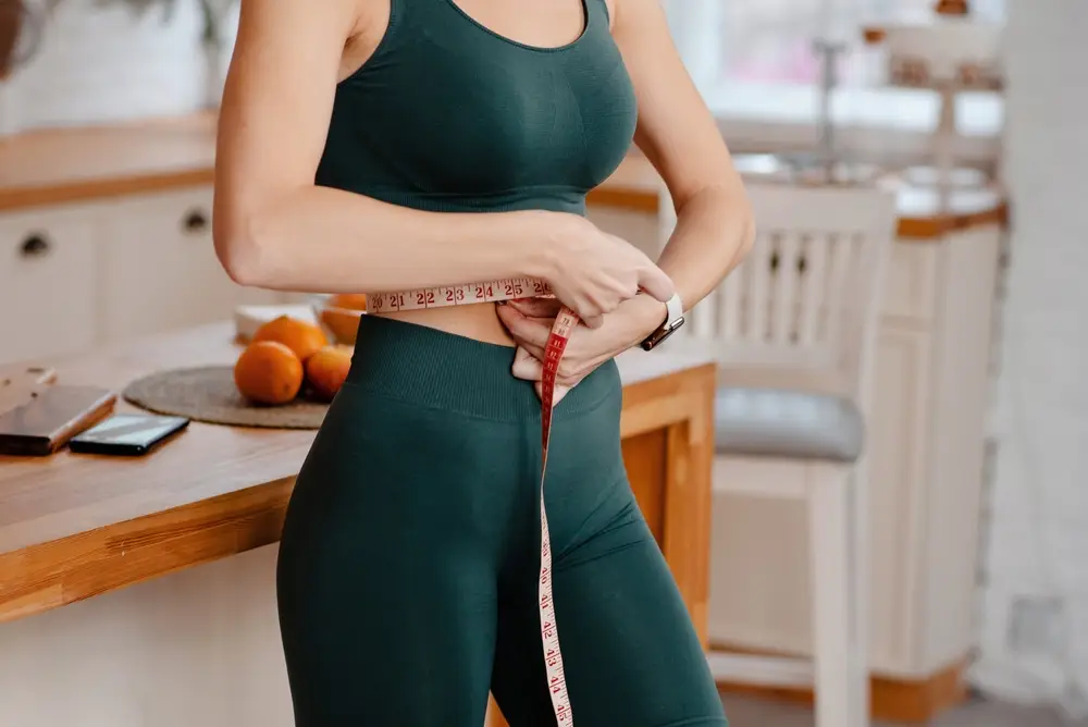 Woman measuring waist for fitness and health